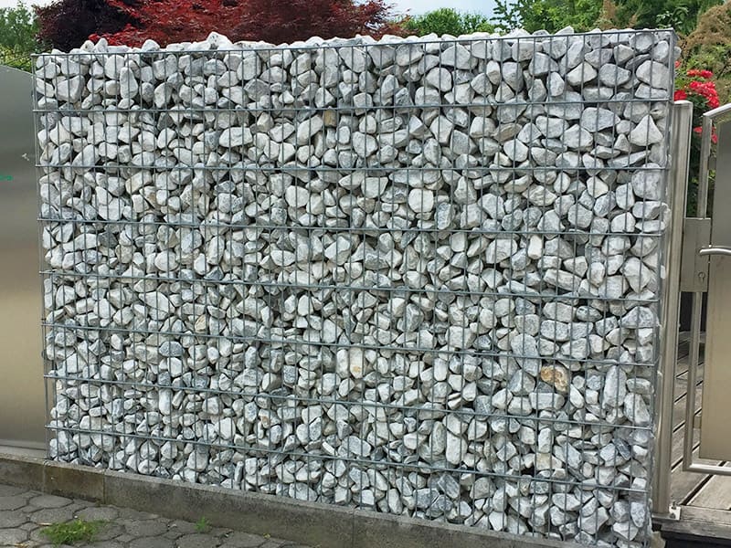 Gambionen mit Natursteinen als Trennmauer