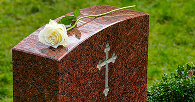 Grabstein aus rotem Granit mit Kreuz und Rose
