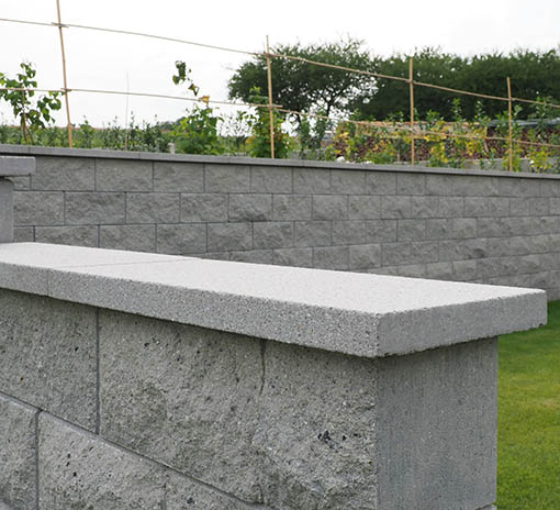 Mauerabdeckplatten mit anthrazitgrauer Stützwand und Sichtschutz in gebrochener Steinoptik aus Beton von BK