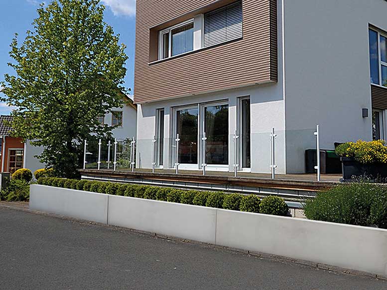 Zaunsockel mit Büschen modernes Haus schlicht Beton Abgrenzung